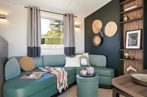 Modern hotel studio at Le Maquis Plage with turquoise sofa, dark accent wall, and coastal decor in Poggio-Mezzana