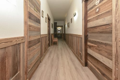 Corridoio dell'Hotel Le Clou ad Arvier con porte in legno, rivestimenti e pavimentazione chiara