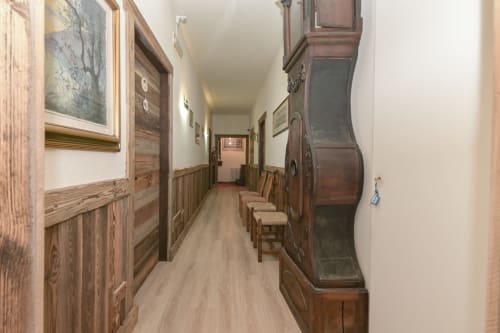 Corridoio dell'Hotel Le Clou ad Arvier con porte in legno, rivestimenti, sedie e mobili antichi