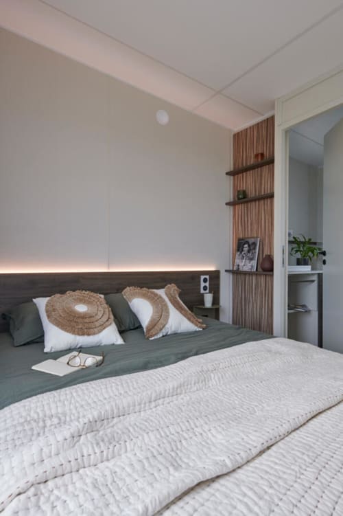 Camera da letto moderna dell'hotel Le Maquis Plage con letto verde, cuscini intrecciati e illuminazione ambiente
