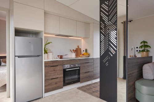 Cucina moderna dell'hotel Le Maquis Plage a Poggio-Mezzana con mobili in legno, elettrodomestici bianchi e piante ornamentali