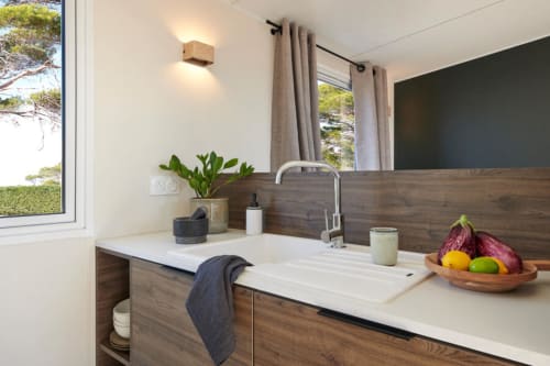 Bagno moderno dell'hotel Le Maquis Plage a Poggio-Mezzana con mobile in legno, lavabo bianco e vista sulla foresta