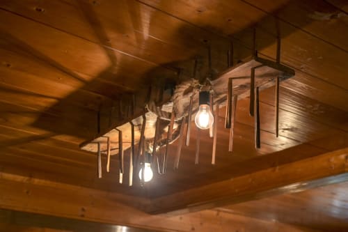Soffitto in legno rustico con lampadari a rami e lampadine luminose all'Hotel Le Clou di Arvier