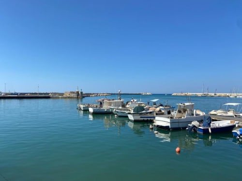 Barche da pesca ormeggiate nel porto di Sciacca con acque turchesi cristalline e cielo azzurro