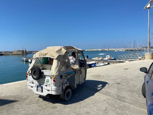 Tuk-tuk taxi parcheggiato al porto di Sciacca con barche a vela e mare Mediterraneo sullo sfondo