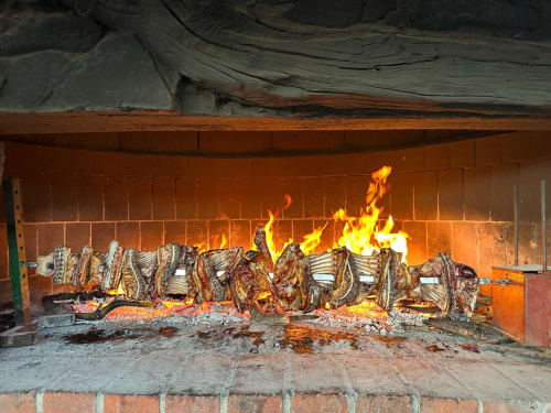 Rustic fireplace with roaring flames and wood logs at Agriturismo Su Barraccu in Loceri, Italy