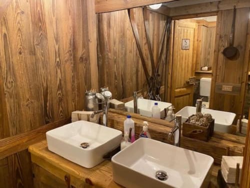 Bagno rustico all'Hotel Le Clou di Arvier con doppi lavabi bianchi, specchio e arredi naturali