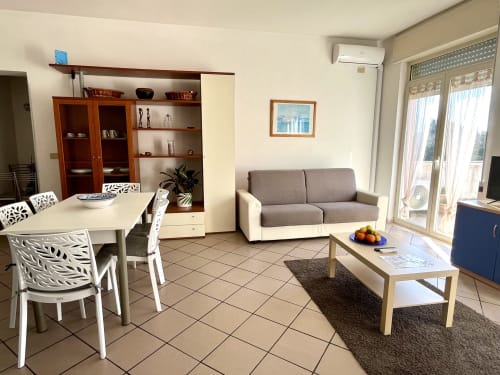 Moderno soggiorno con divano, zona pranzo, accesso al balcone e arredi in legno a Tirreno