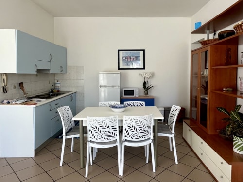 Moderna zona cucina-soggiorno dell'Apartment Tirreno a Tirrenia con sedie bianche e mobili blu