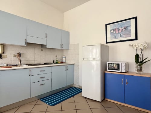 Cucina moderna dell'Apartment Tirreno a Tirrenia con mobili azzurri, elettrodomestici bianchi e mobile contenitore blu