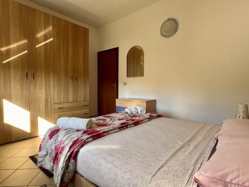 Camera luminosa dell'Apartment Tirreno a Tirrenia con armadio in legno, biancheria floreale e specchio a parete