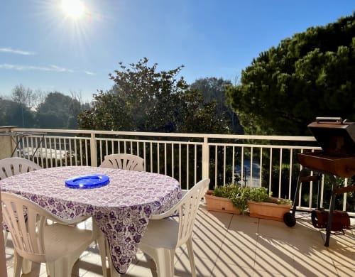 Balcone soleggiato dell'Apartment Tirreno a Tirrenia con tavolo da pranzo, sedie, barbecue e vista sul mare
