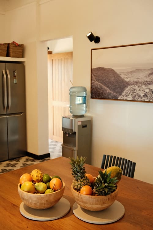 Cocina del Seaflower Lodge con cuencos de frutas de madera, electrodomésticos de acero inoxidable y cuadros de paisajes montañosos en paredes color crema.