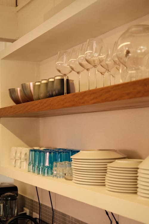 Estantes de cocina organizados en la posada boutique Seaflower mostrando copas de vino, platos y tazas color azul verdoso en San Andrés