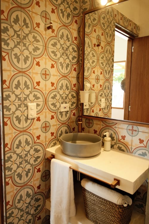 Baño de la boutique lodge Seaflower con azulejos decorativos en tonos rojo y beige, lavamanos tipo recipiente, espejo y detalles de madera en San