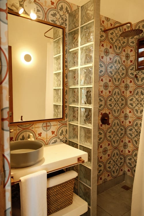Baño de la boutique lodge Seaflower con azulejos decorativos españoles, lavabo tipo recipiente, espejo y divisor de ducha de bloques de vidrio