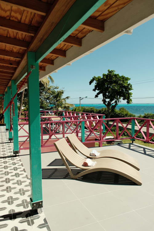 Terraza de Seaflower boutique lodge con pilares verdes, barandillas burdeos, tumbonas frente al Mar Caribe, San Andrés