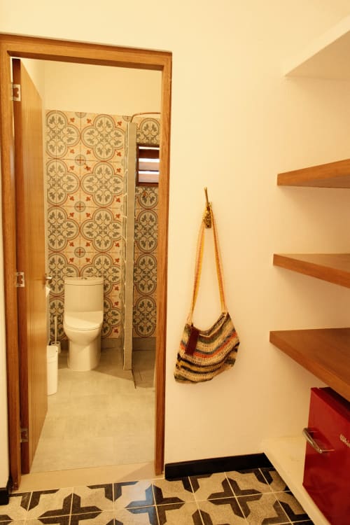 Entrada del baño de Seaflower Lodge con ornamentación de azulejos, estantes de madera y bolsa tejida en San Andrés