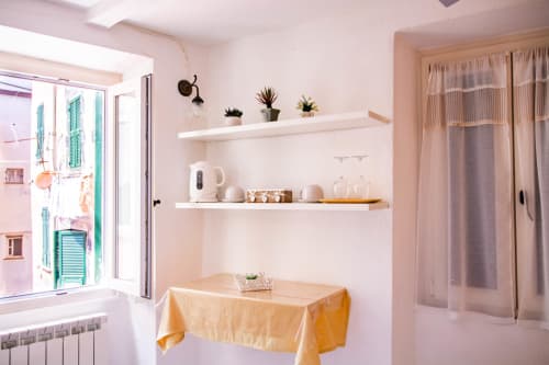 Camera luminosa e minimalista a SoleMagia a Vernazza con scaffali bianchi, tavolo in legno, vista sulla città e comfort moderni