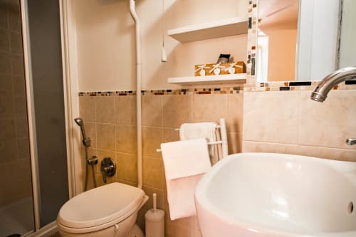Bagno moderno presso SoleMagia B&B a Vernazza con lavabo bianco, wc e zona doccia piastrellata con ripiani per gli articoli da toilette