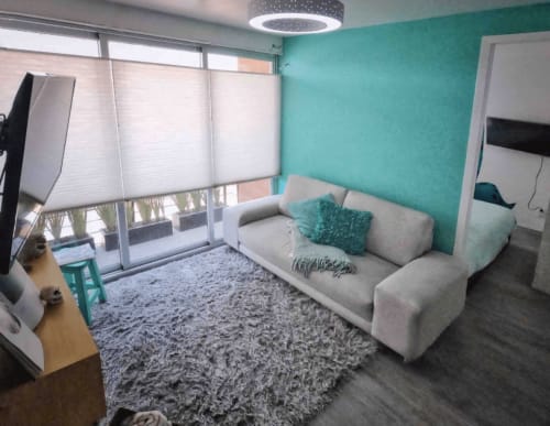 Sala turquesa de Pares Homes en CDMX con sofá beige, tapete gris y lámpara colgante moderna