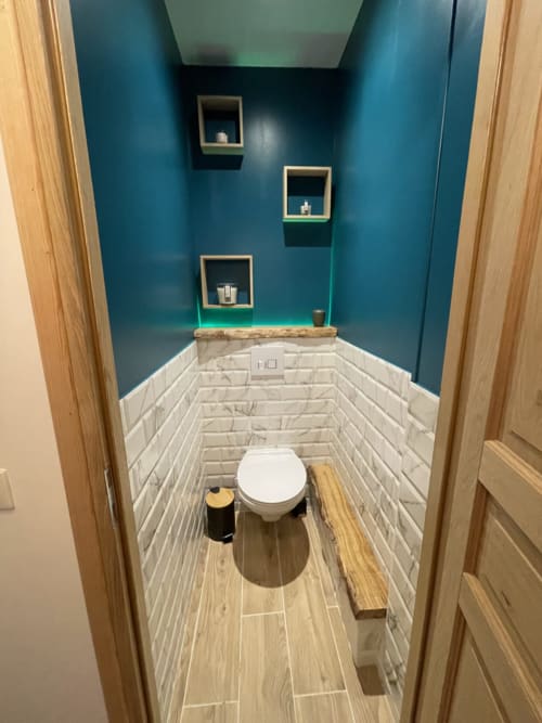 Salle de bains moderne aux murs bleu-vert, briques blanches, plancher bois et étagères flottantes à la Suite d'amour à Chartrettes
