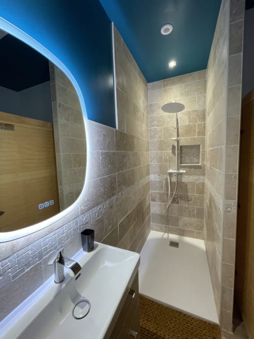 Salle de bain moderne avec miroir illuminé, pomme de douche pluie et carrelage beige à la Suite d'amour, Chartrettes