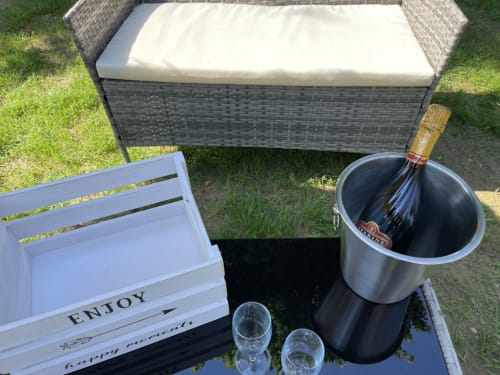 Aménagement de terrasse au Suite d'amour avec banc en rotin, seau à champagne, verres à vin et coffre en bois à Chartrettes