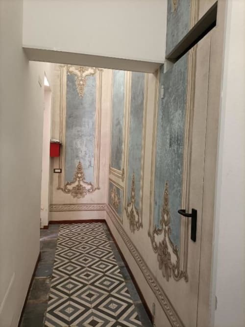 Elegante corridoio in appartamento Belle Époque a Oristano, con pavimentazione in piastrelle geometriche e pannelli murali ornati
