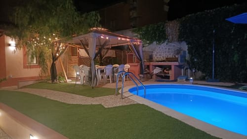 Villa Belle Époque vista notturna della piscina con gazebo illuminato, area relax e piscina blu luminosa a Oristano