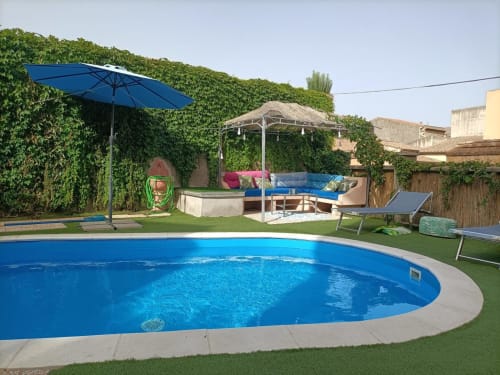 Area piscina invitante di Maison Belle Époque con ombrellone blu, lettini e muri ricoperti di edera a Oristano