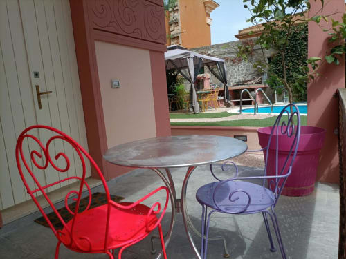 Sedie metalliche rosse e viola al tavolo della terrazza, vista piscina di Maison Belle Époque, Oristano