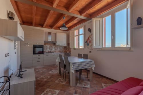 Cucina moderna e zona pranzo di Maison Belle Époque a Oristano con travi in legno e pavimenti in cotto