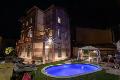 Villa Belle Époque a Oristano di notte con villa illuminata, piscina splendente e area lounge esterna