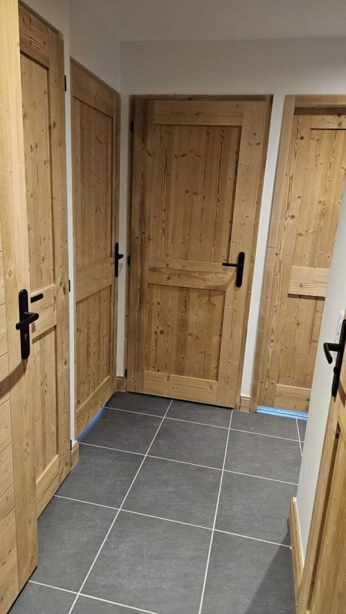 Couloir avec quatre portes en bois et sol en ardoise de l'appartement L'écrin des sapins à Aime-la-Plagne