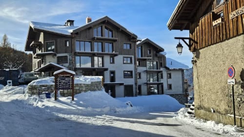 Façade de l'appartement L'écrin des sapins enneigé à Aime-la-Plagne avec vue sur les montagnes et architecture alpine
