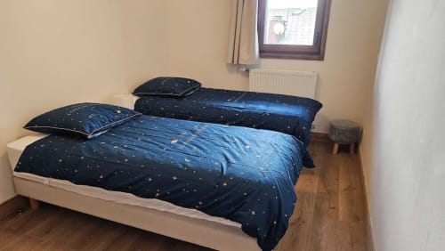 Chambre douillette à L'écrin des sapins à Aime-la-Plagne avec literie bleu marine à motifs étoilés, deux lits et parquet.