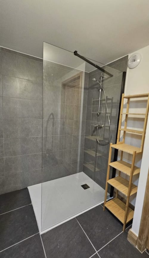 Salle de bain moderne à L'écrin des sapins avec douche à l'italienne, carrelage foncé, socle blanc, étagères en bois, Aime-la-Plagne