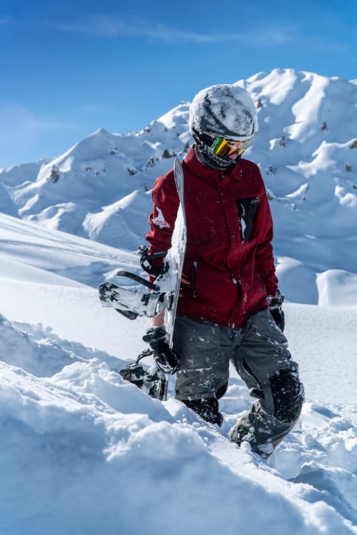 Snowboardeur en veste rouge sur une piste enneigée à la station de ski d'Aime-la-Plagne, Savoie