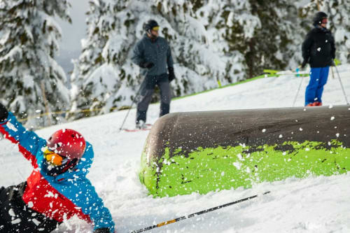 Enfant skiant à L'écrin des sapins avec des sapins enneigés et des skieurs à Aime-la-Plagne