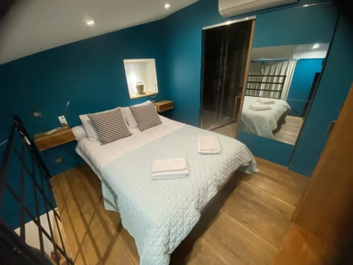 Modern bedroom with turquoise walls, queen bed, and mirror at AJOUCADOU BnB in Lourmarin