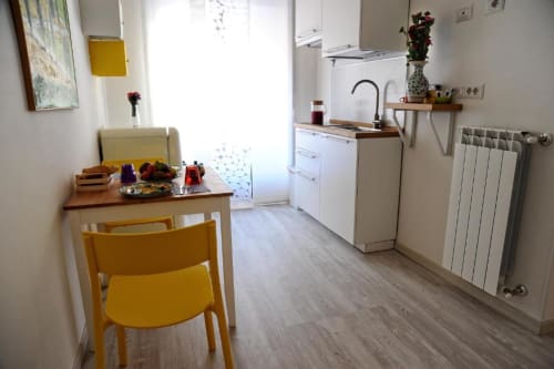 Bright Deluxe Studio kitchen in Casa Castagna, Salerno, with yellow chair, dining table, white appliances and wood flooring