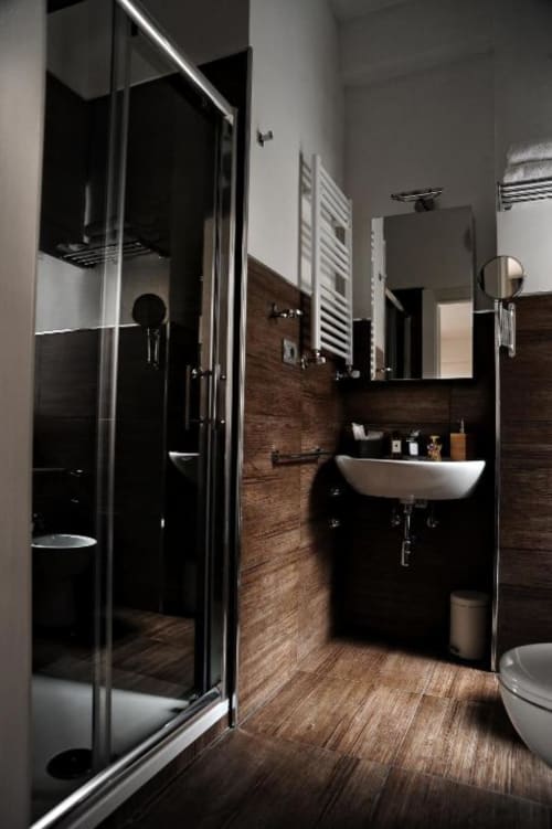 Modern bathroom in Casa Castagna Deluxe Room, Salerno with black marble, vessel sink, walk-in shower, and white towel rack
