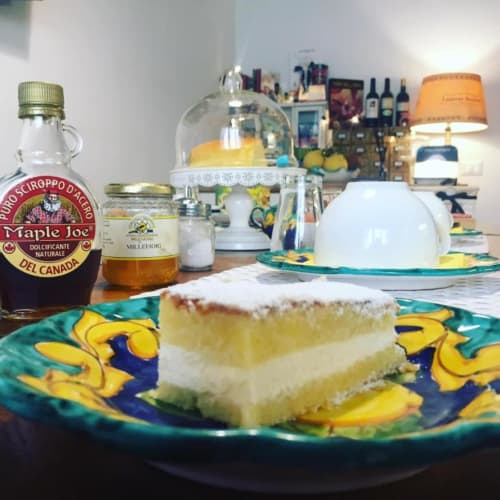 Slice of cream cake on decorative plate with maple syrup bottle in Salerno B&B room