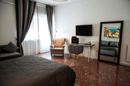 Deluxe double room at Casa Castagna in Salerno with TV, armchair, desk, mirror, and terracotta floor