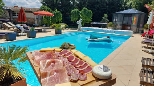 La piscine de La Bergerie Du Moulin avec plateau de charcuterie, terrasse ensoleillée et baigneur à Taradeau.