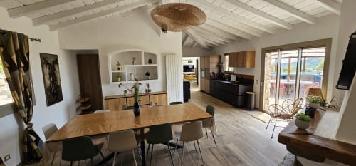 Modern villa dining area with sea views, wooden table, contemporary chairs, open kitchen, and bright coastal décor at