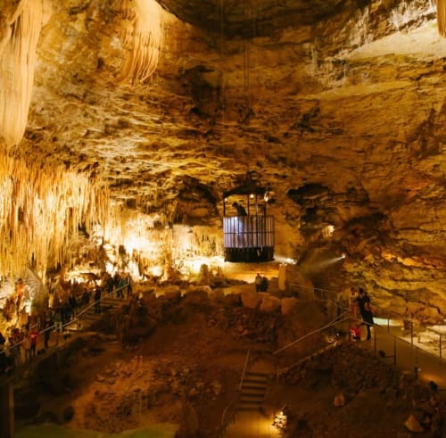 Galerie souterraine avec stalactites, allées éclairées et visiteurs à Maisonaurinko près de Thénon, France