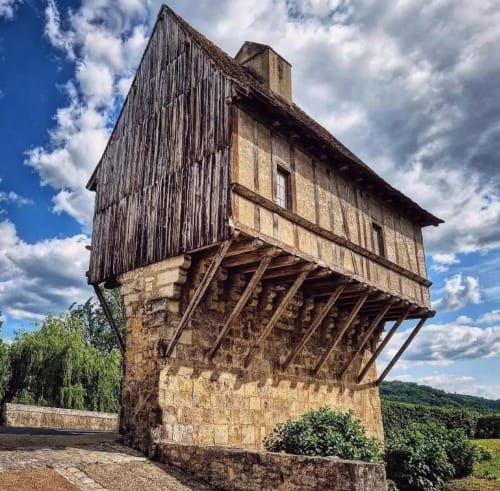 Tour en pierre médiévale avec colombage à la Maison Aurinko B&B à Thénon, France, sous un ciel nuageux