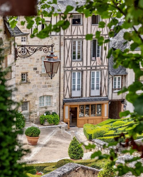 Cour du gîte Maisonaurinko à Thénon avec bâtiments médiévaux à colombages et jardins soignés